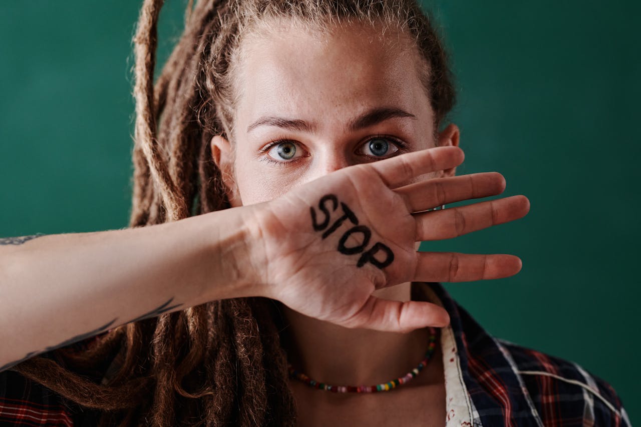 lady with blonde locs with her hand up to her face, with the word stop written in it