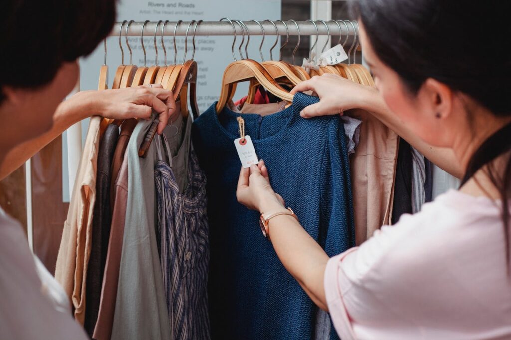 two women looking at the price tag ona blue shirt at a thrift store