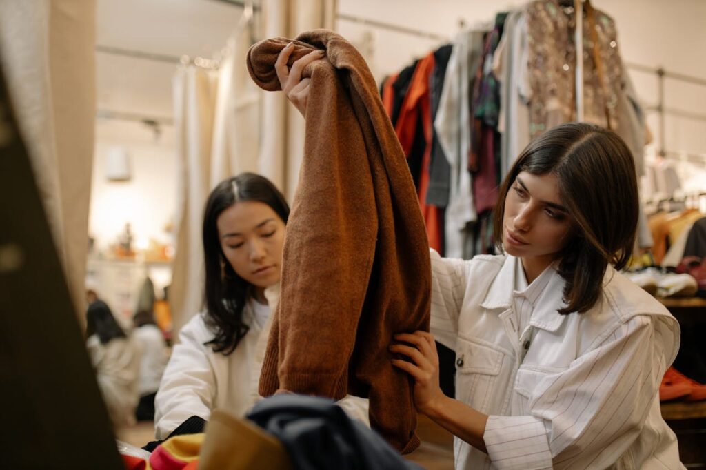 two women shopping at a store feeling the quality of a garment