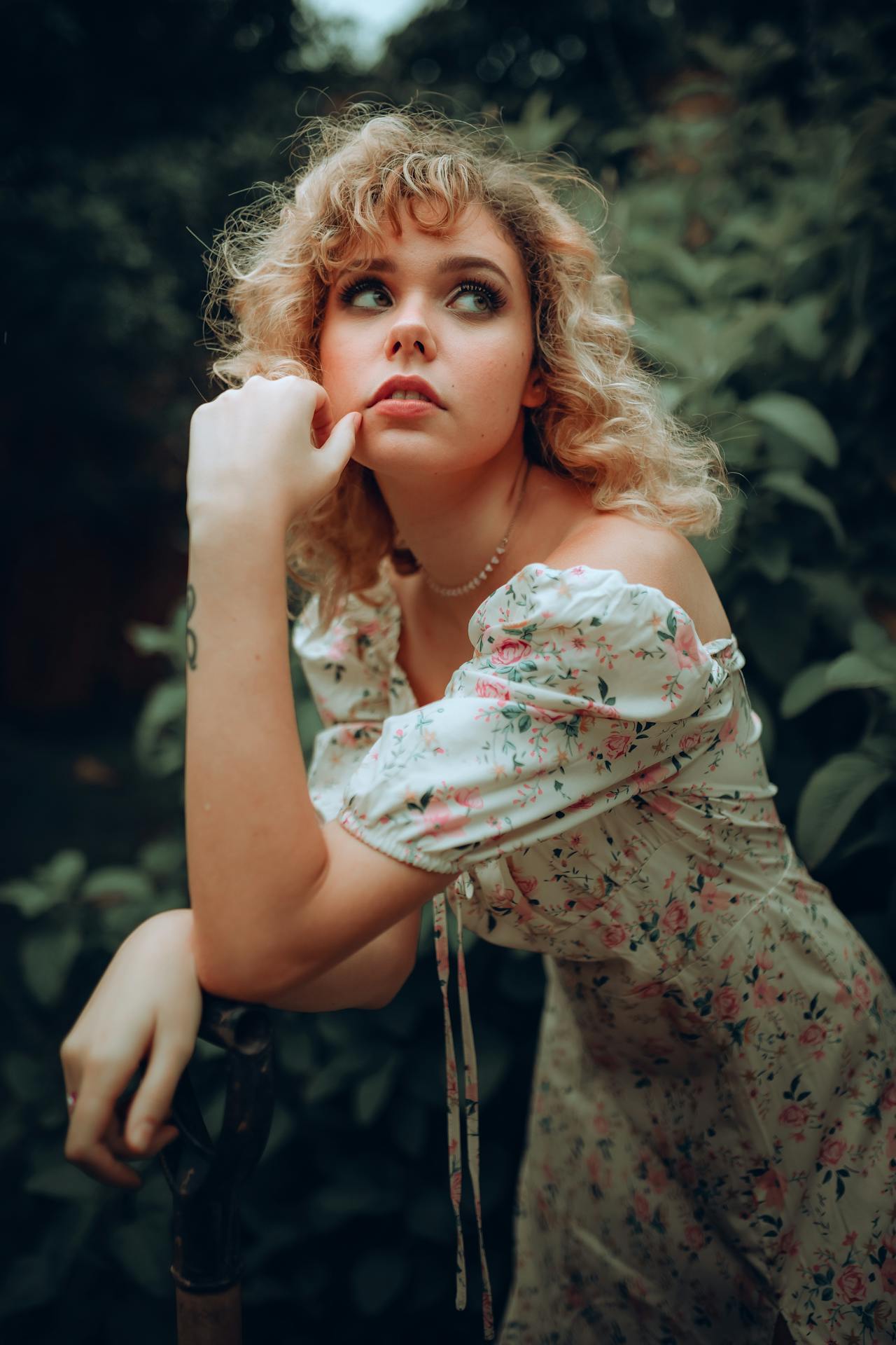 girl in a flower floral print dress perfect for spring outfit time with dark green trees in the background