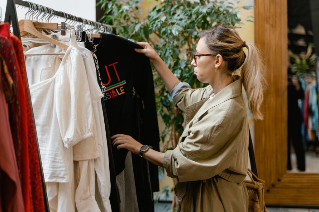 woman looking at a black shirt with colorful writing on the rack at the thrift store