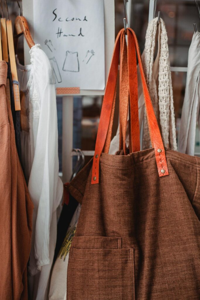 clothes and a brown bag on a rack at a secondhand thrift store