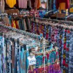 racks of clothes, colorful skirts and pants at the thrift store