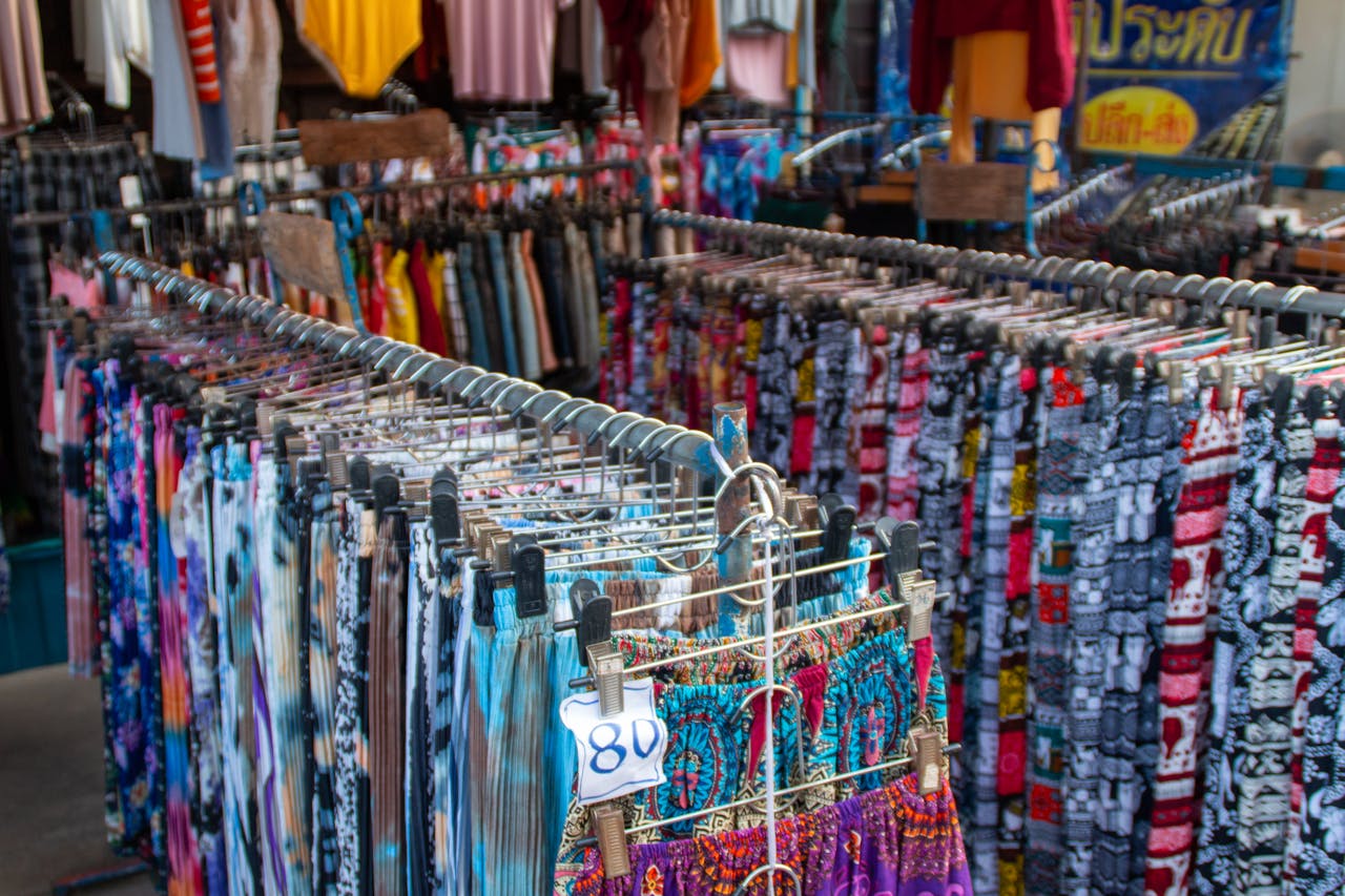 racks of clothes, colorful skirts and pants at the thrift store