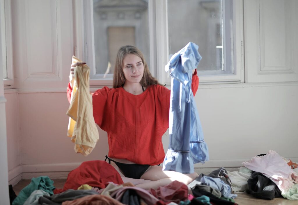 woman sorting through a pile of thrifted clothes to be cleaned