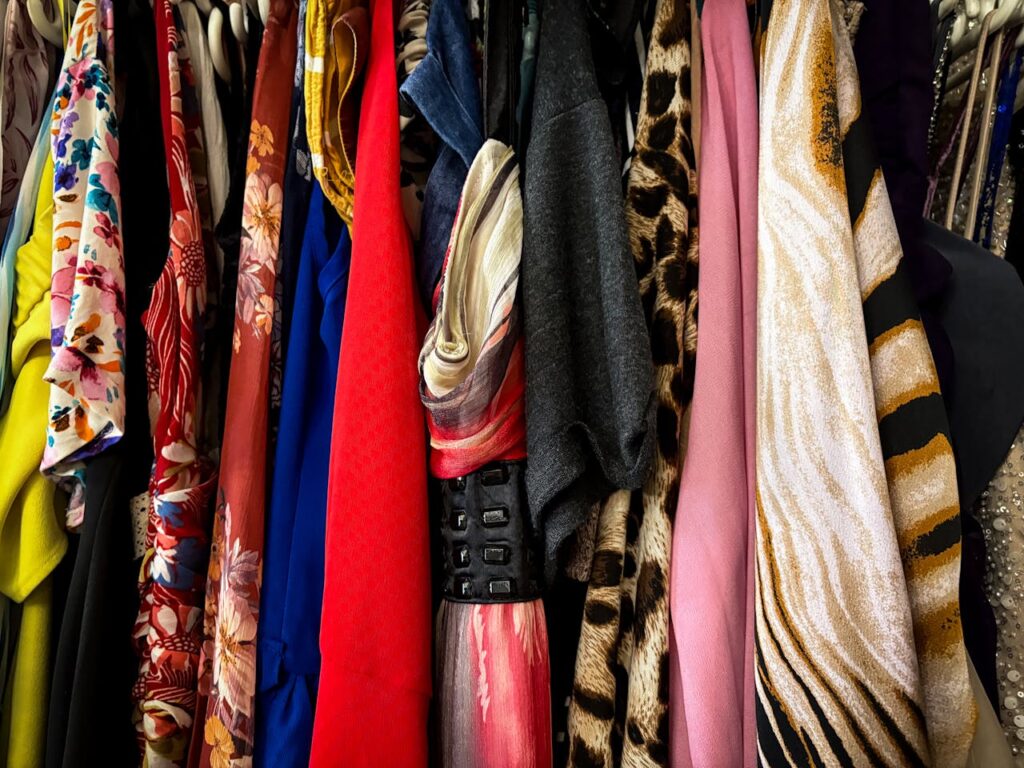 a collection of vintage clothes on a rack at the thrift store